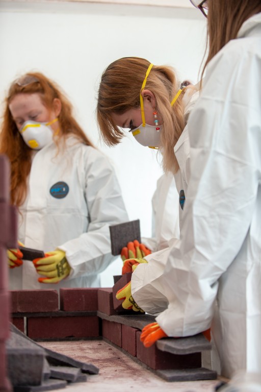 A group of people wearing PPE, making a brick wall