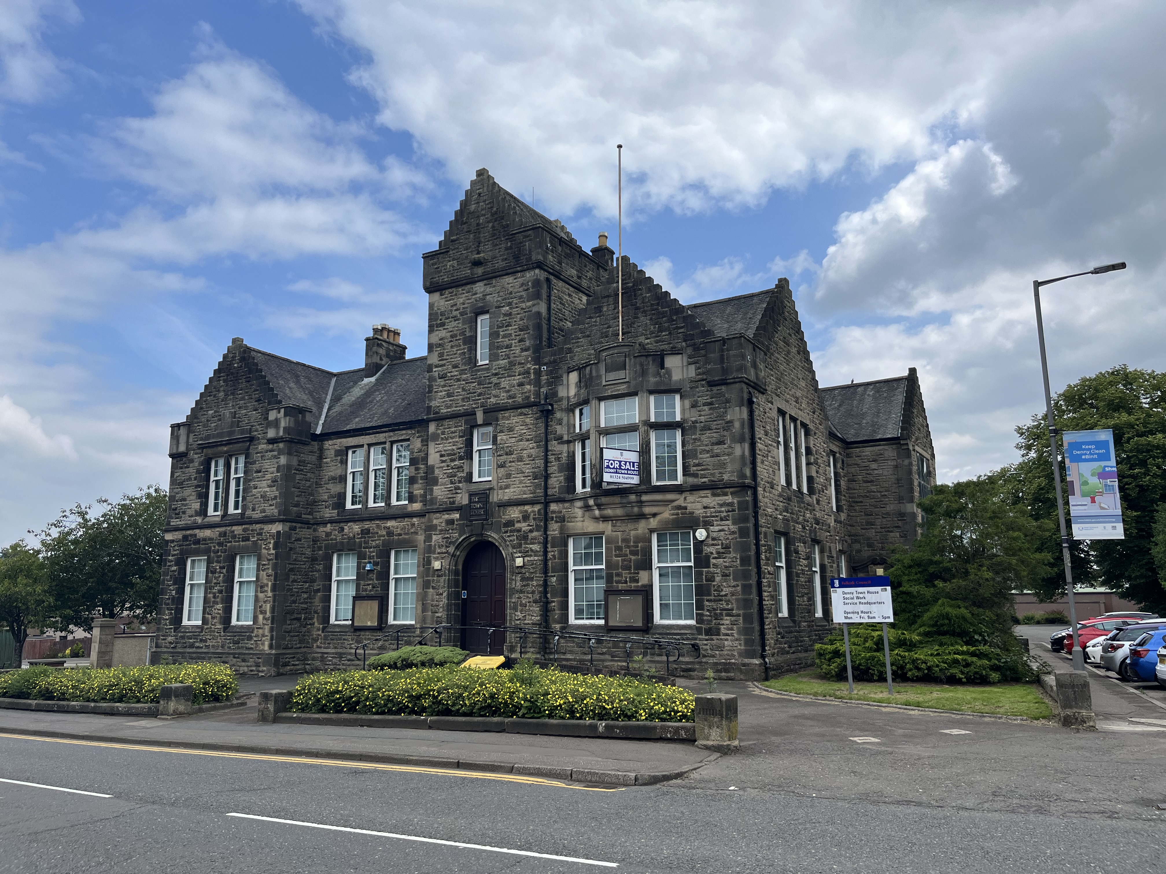 Main elevation of Denny town house - large dark grey building, blue sky behind