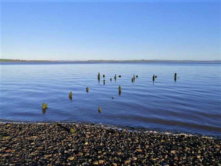 Carsethorn Pier, tops of wooden posts visible at high tide on a sunny day