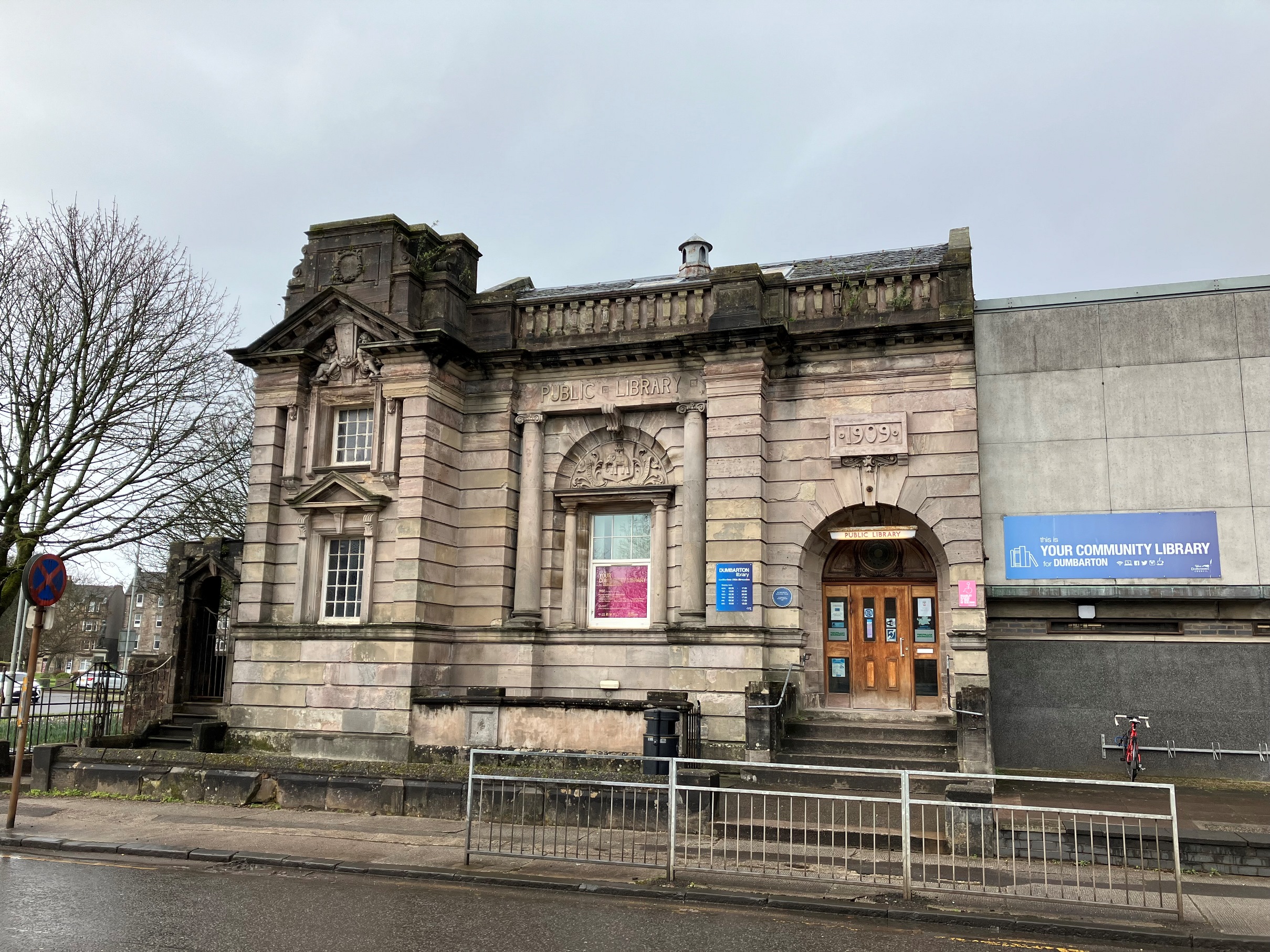 Library fronting pavement with tree in left foreground