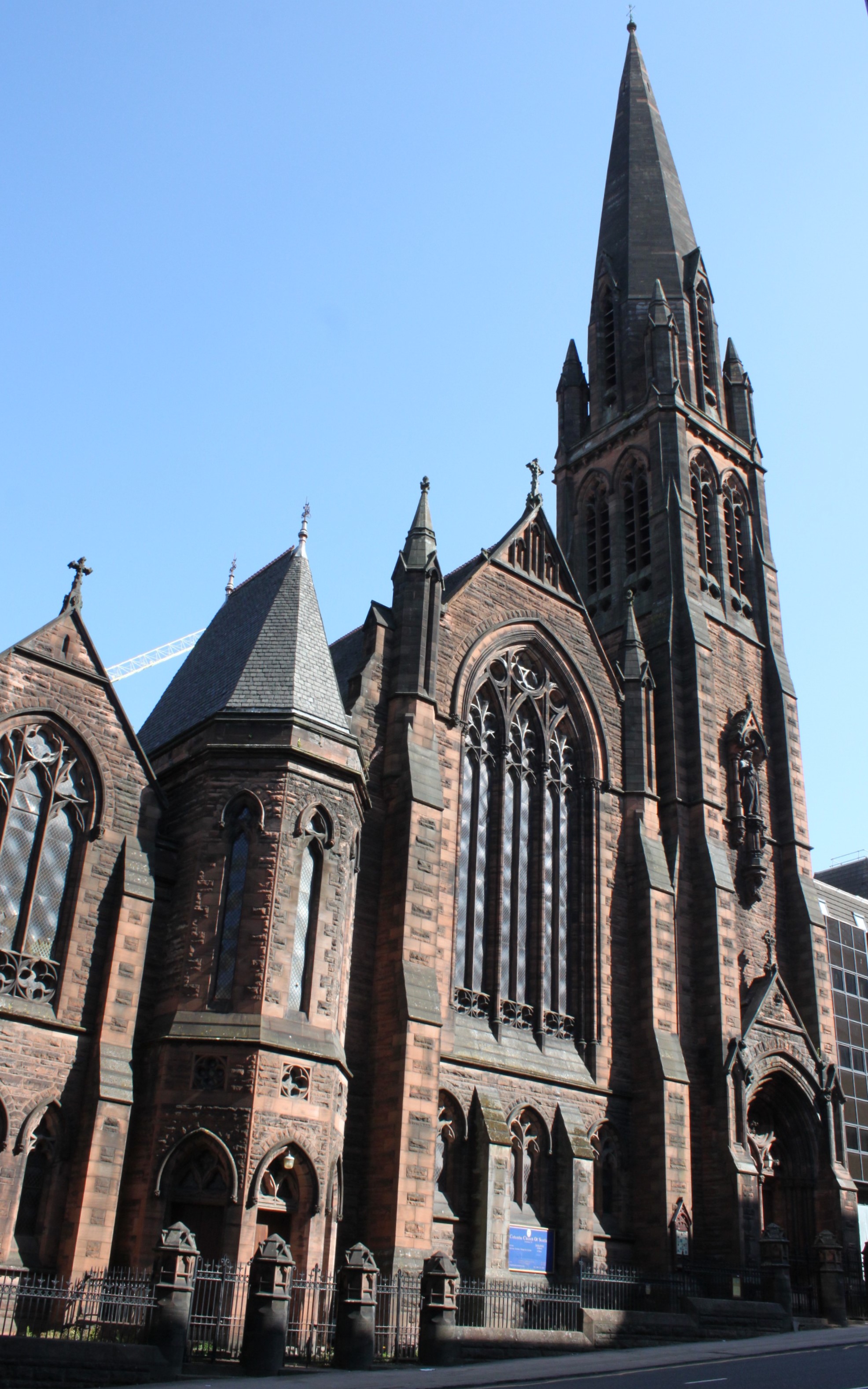Large red sandstone church building against blue sky background.
